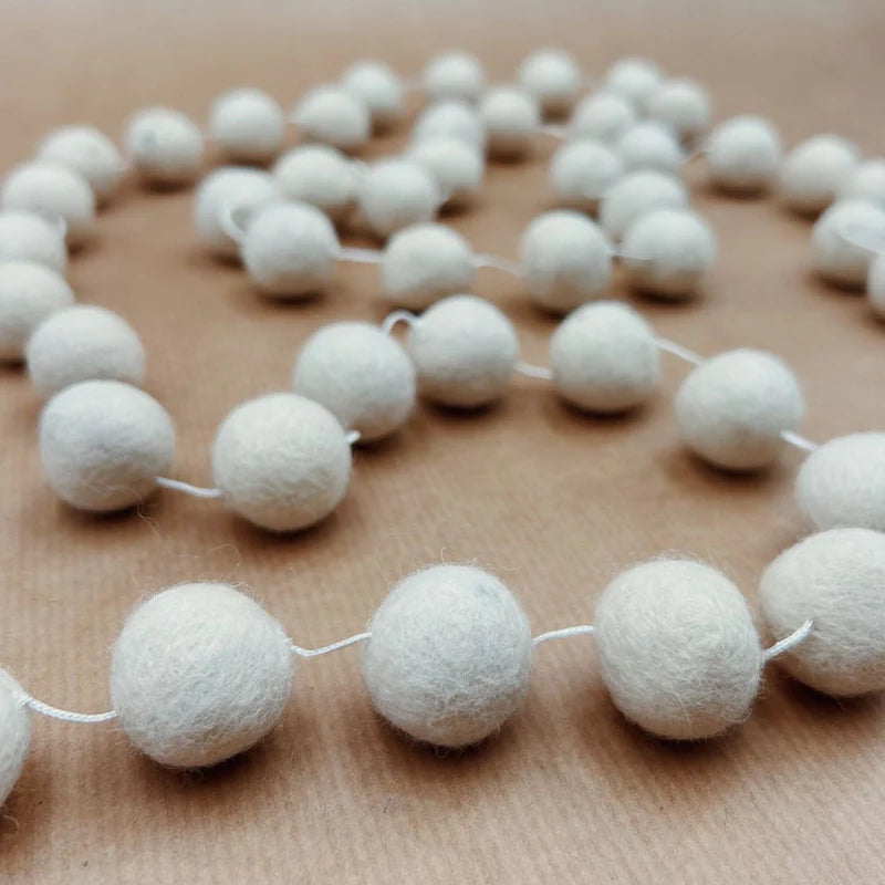 Gros plan sur les boules en laine blanche de la guirlande artisanale New Heidi.