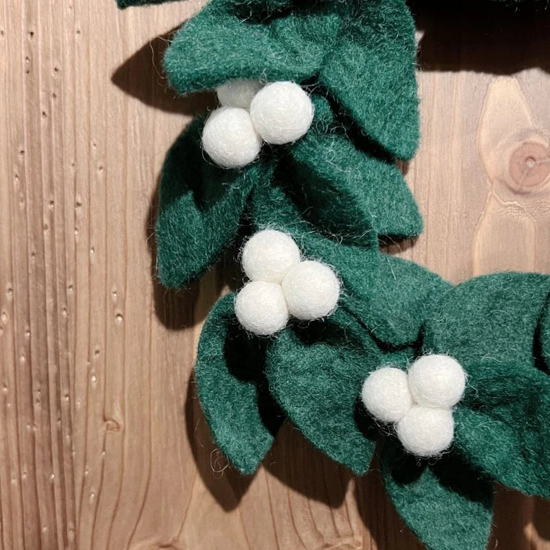 Détail des baies blanches de gui et feuilles de houx faites main en feutrine de laine.