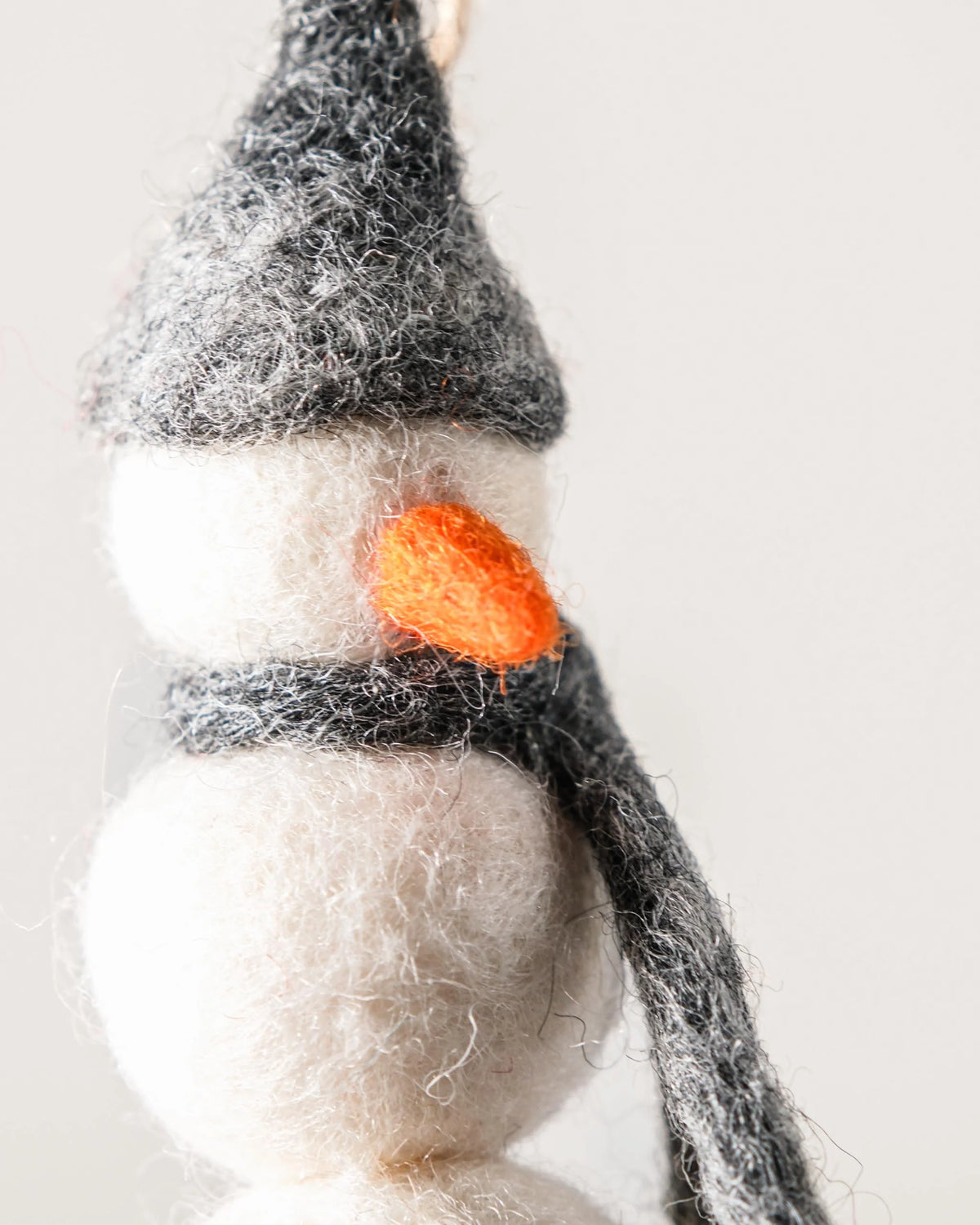 Petit bonhomme de neige a suspendre en feutrine sur un fond blanc détail zoom matière.
