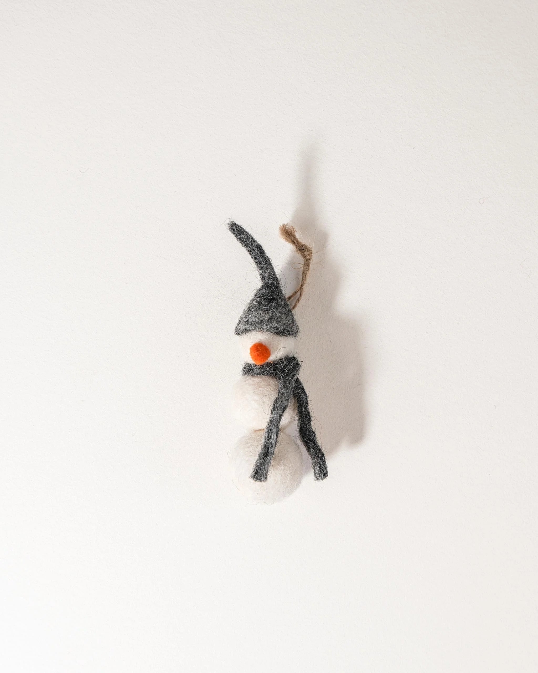 Petit bonhomme de neige a suspendre en feutrine sur un fond blanc.