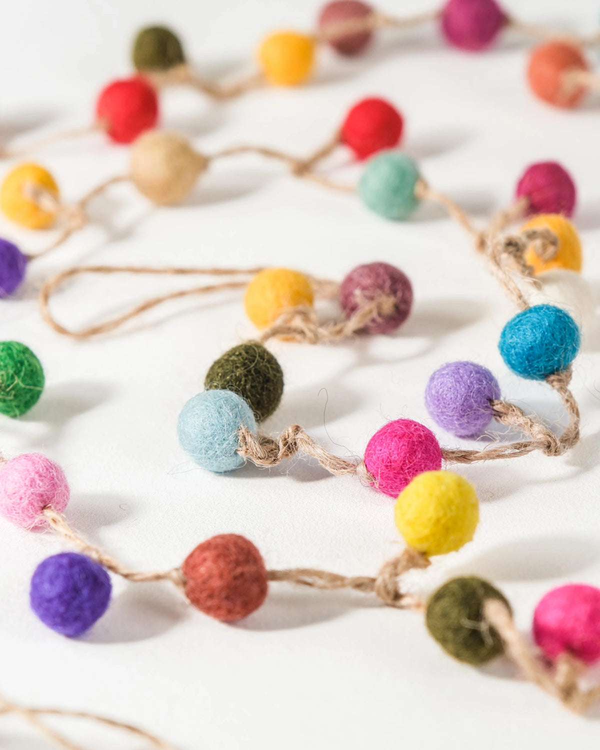 GUIRLANDE PETITE BOULE MULTICOLORE SUR UN FOND BLANC DÉTAIL ZOOM MATIÈRE.