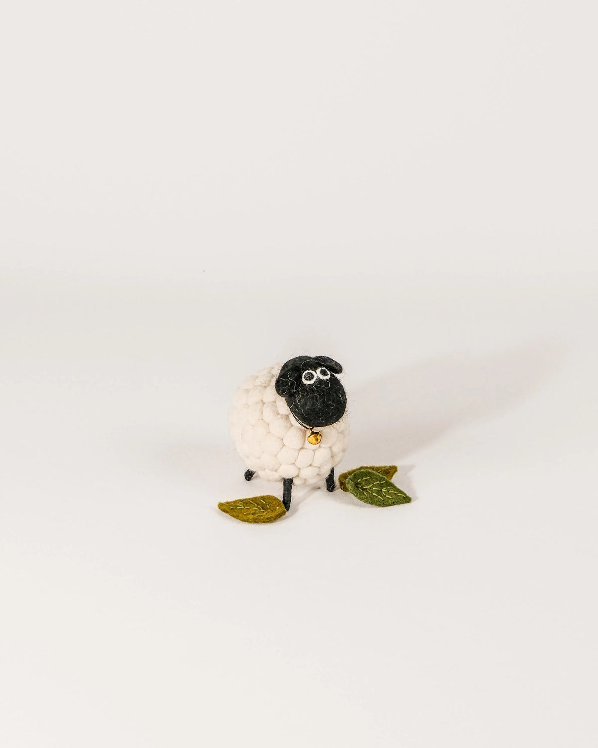 Petit mouton boule tête noir sur un fond blanc.
