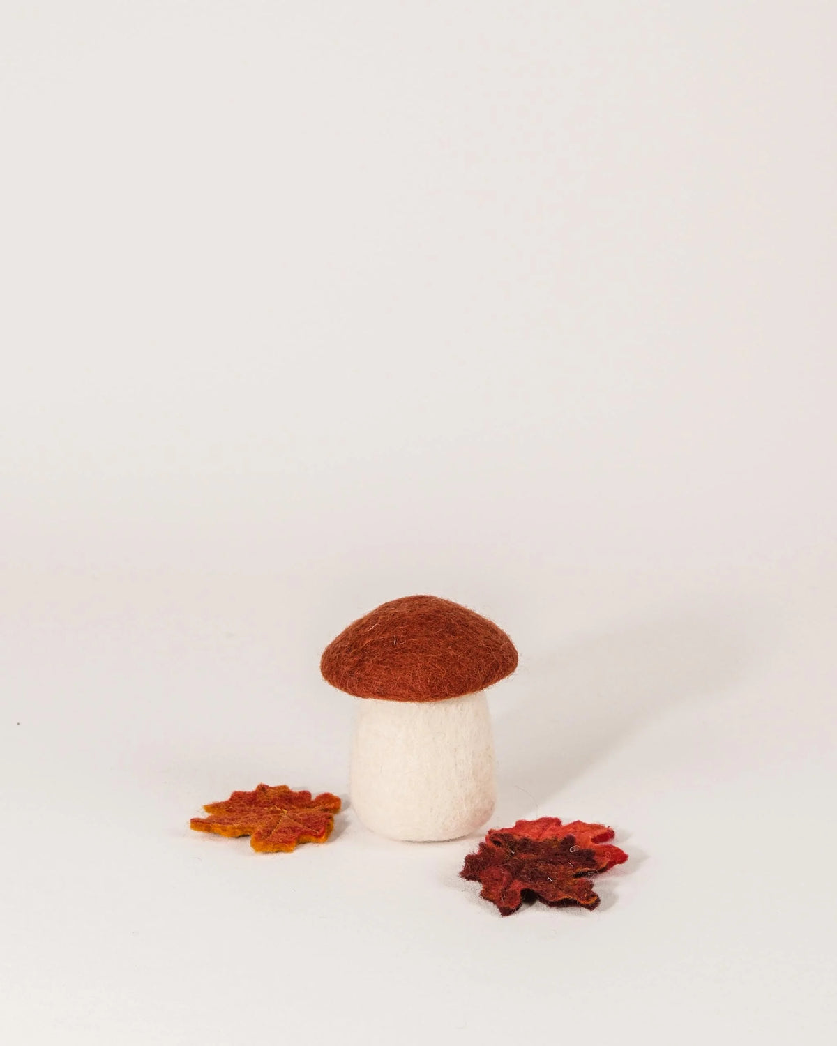 Grand champignon rouille en feutrine sur un fond blanc.