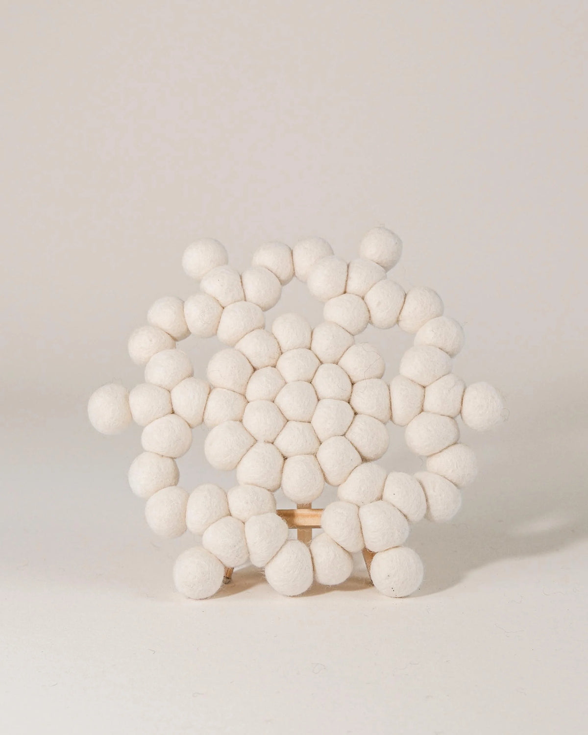 Dessous de plat boule en feutrine flocon sur un fond blanc.