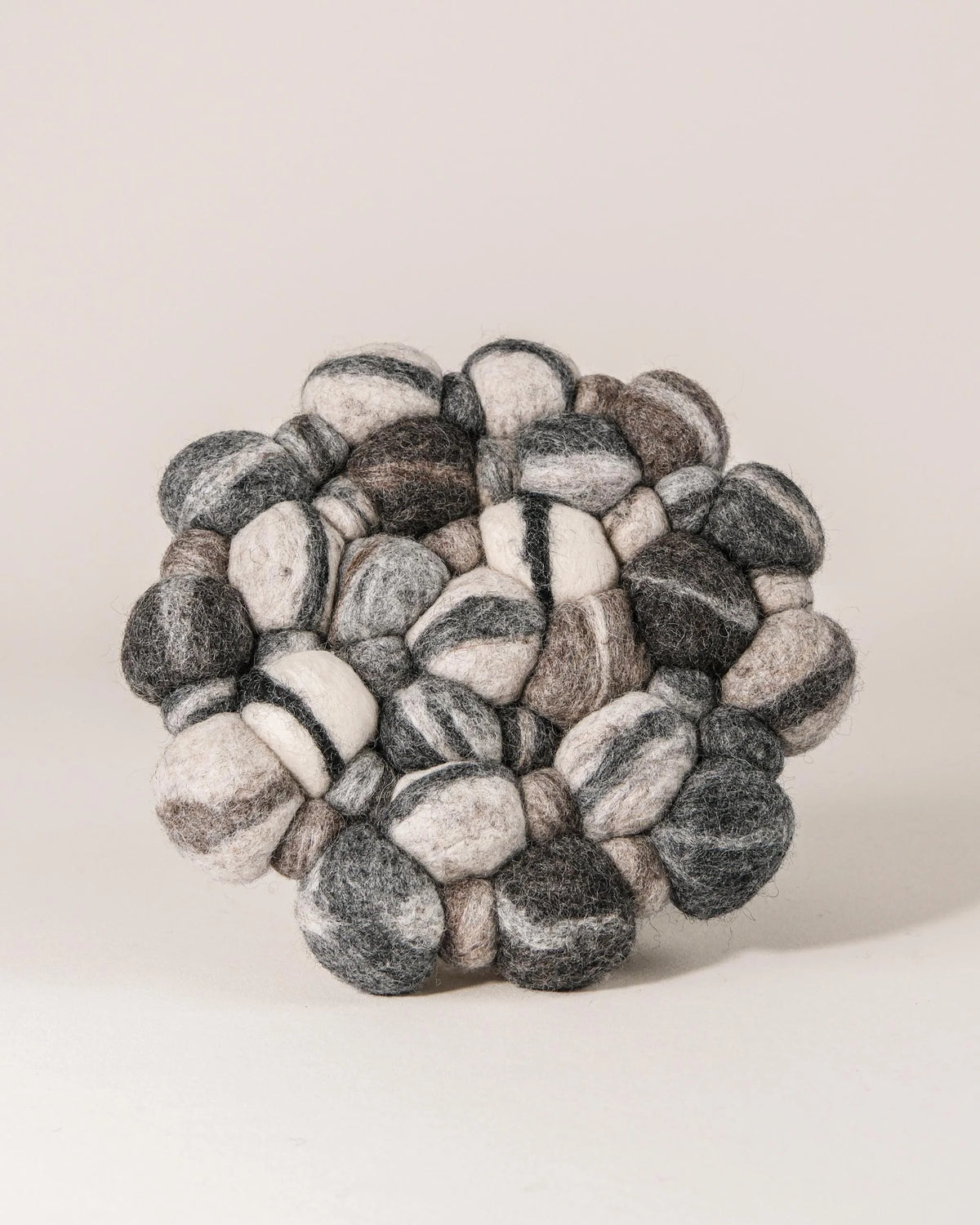 Dessous de plat boule en feutrine gros galet rond sur un fond blanc.