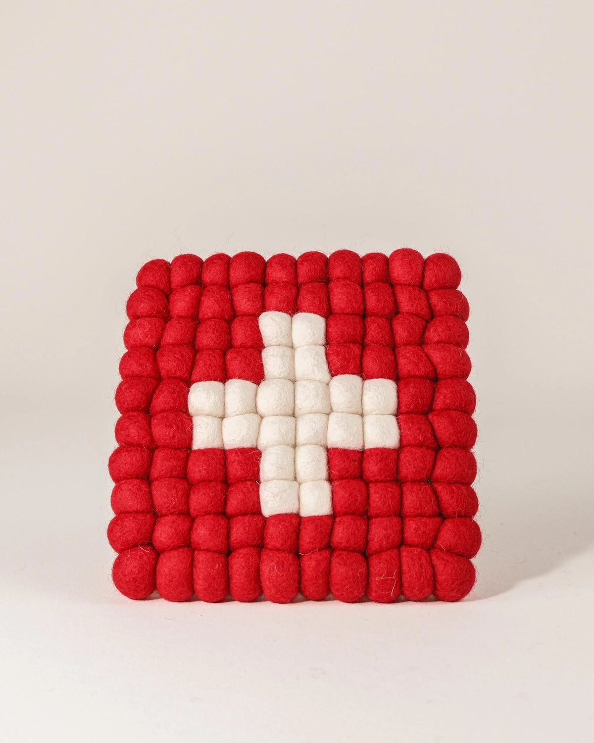 Dessous de plat boule en feutrine drapeau Suisse sur un fond blanc.