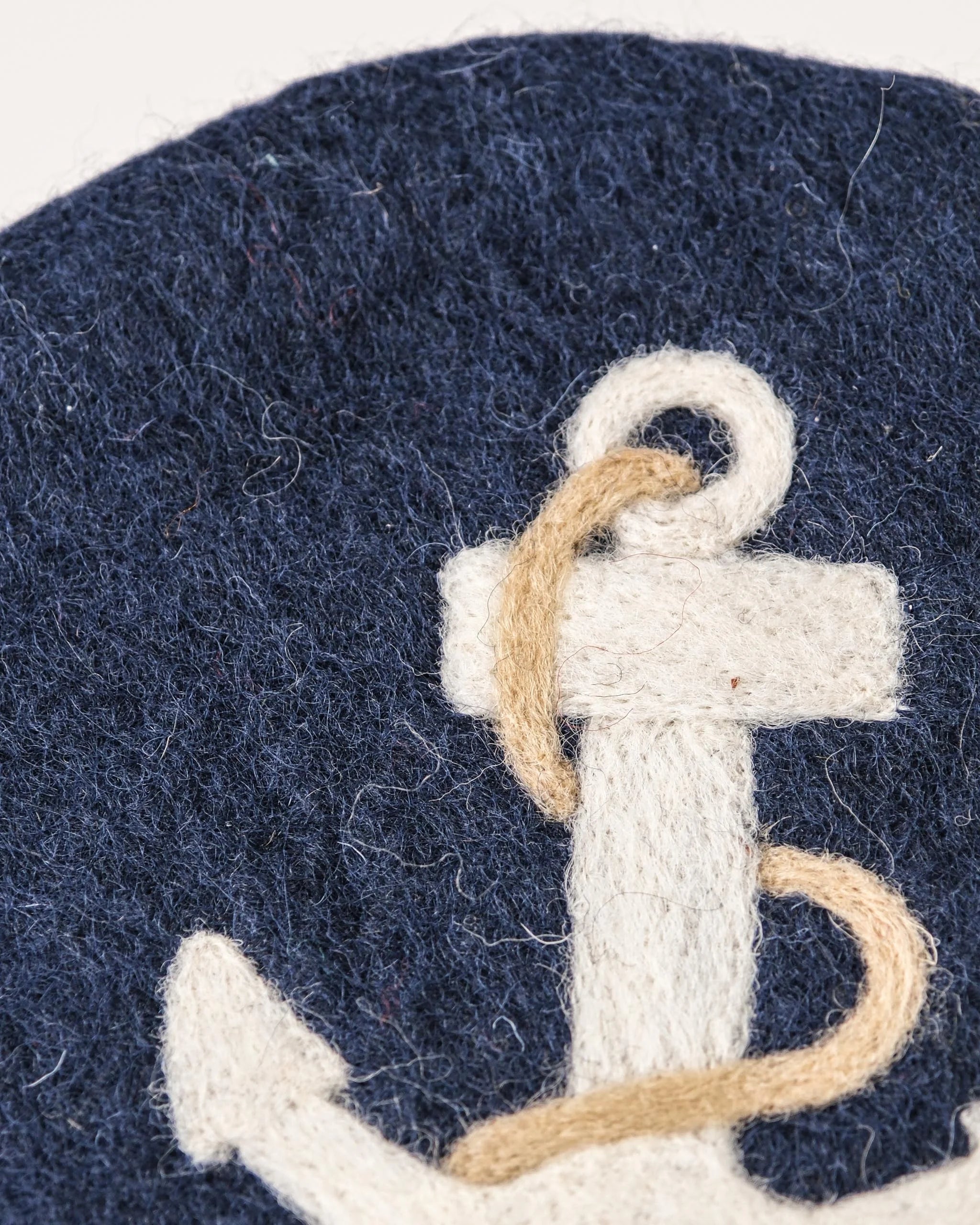 Dessous de plat boule en feutrine motif ancre sur un fond blanc détail zoom matière.