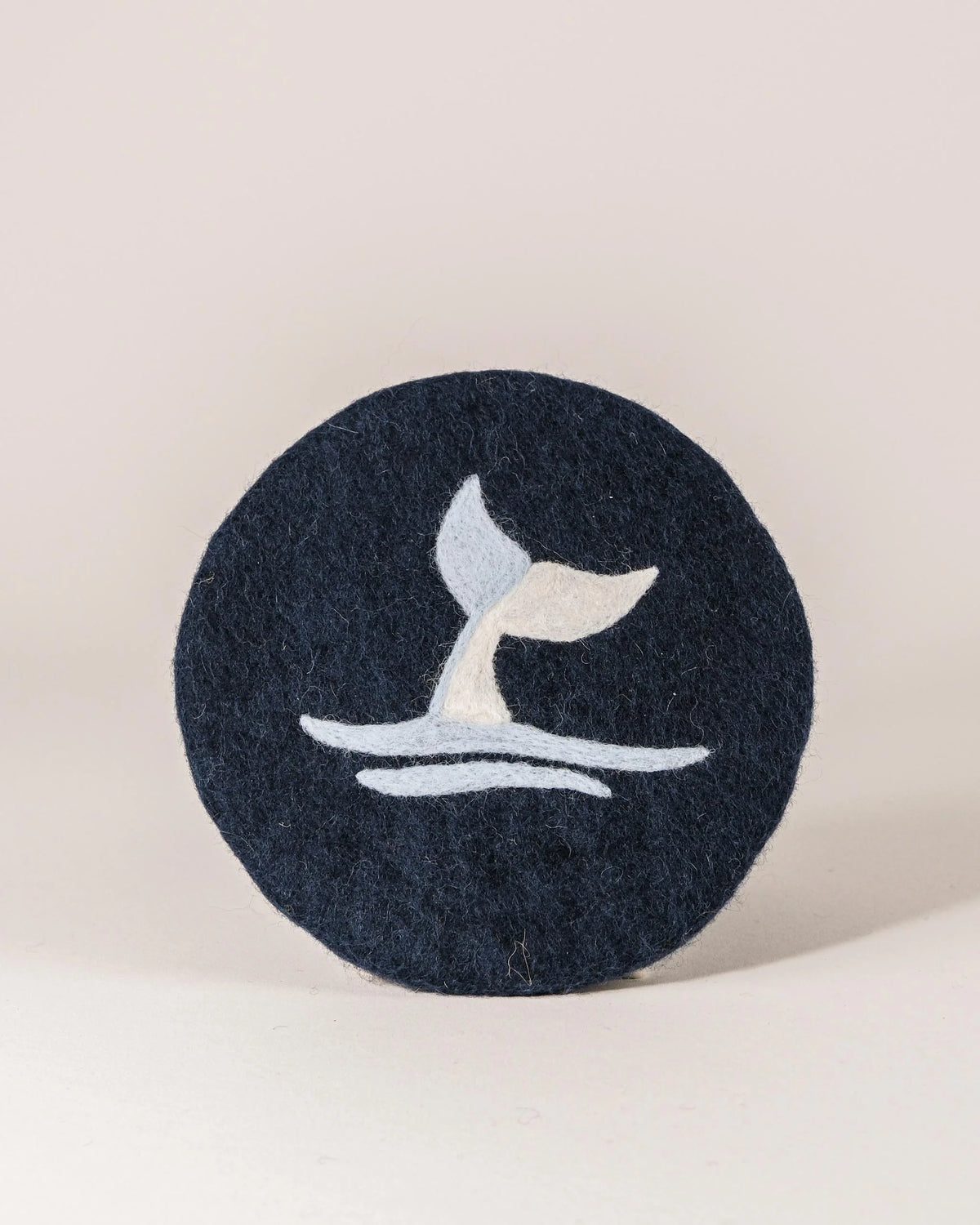 Dessous de plat boule en feutrine motif baleine sur un fond blanc.