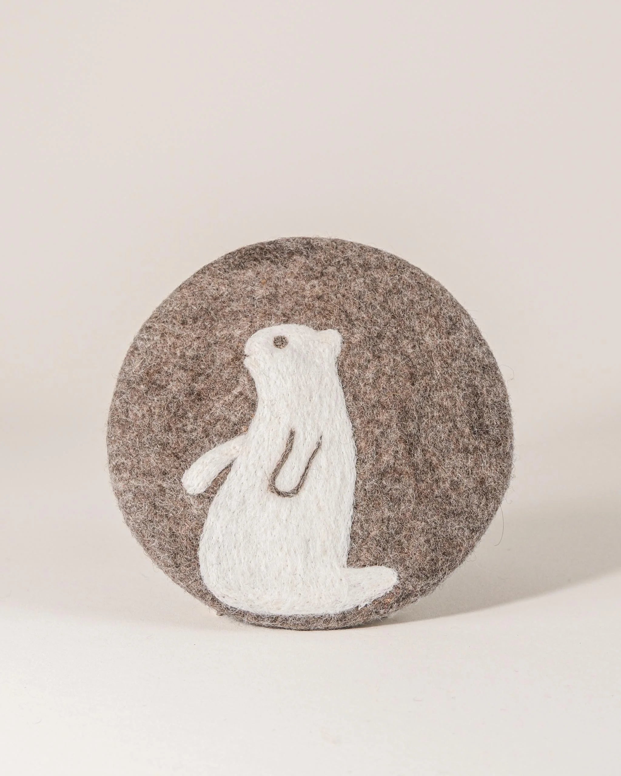 Dessous de plat boule en feutrine motif marmotte sur un fond blanc.