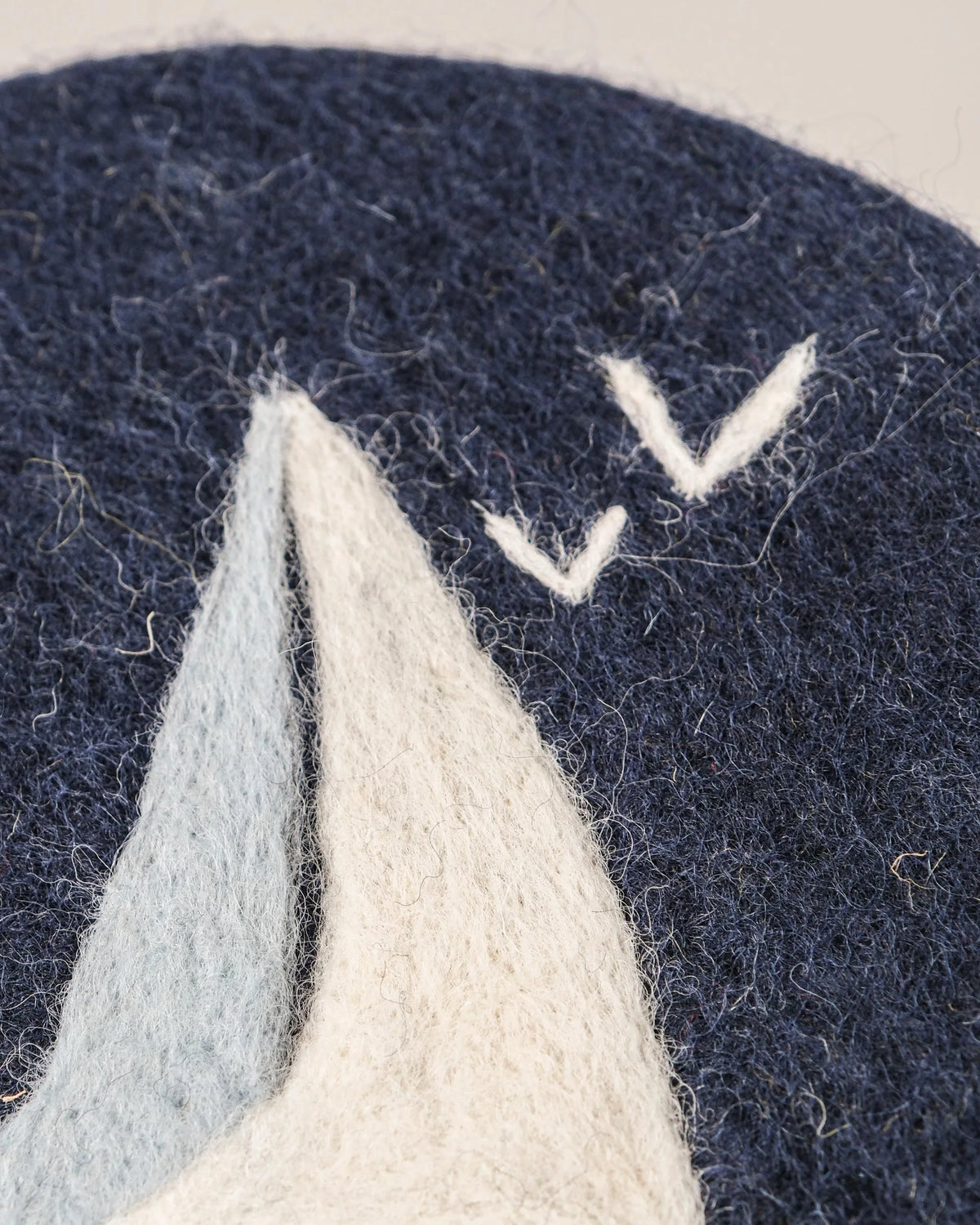 Dessous de plat boule en feutrine motif voilier sur un fond blanc détail zoom matière.
