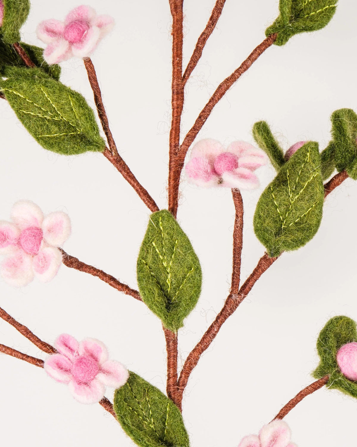 Photo zoom d'une fleurs de pommier en feutrine sur un fond blanc style photo packshot.