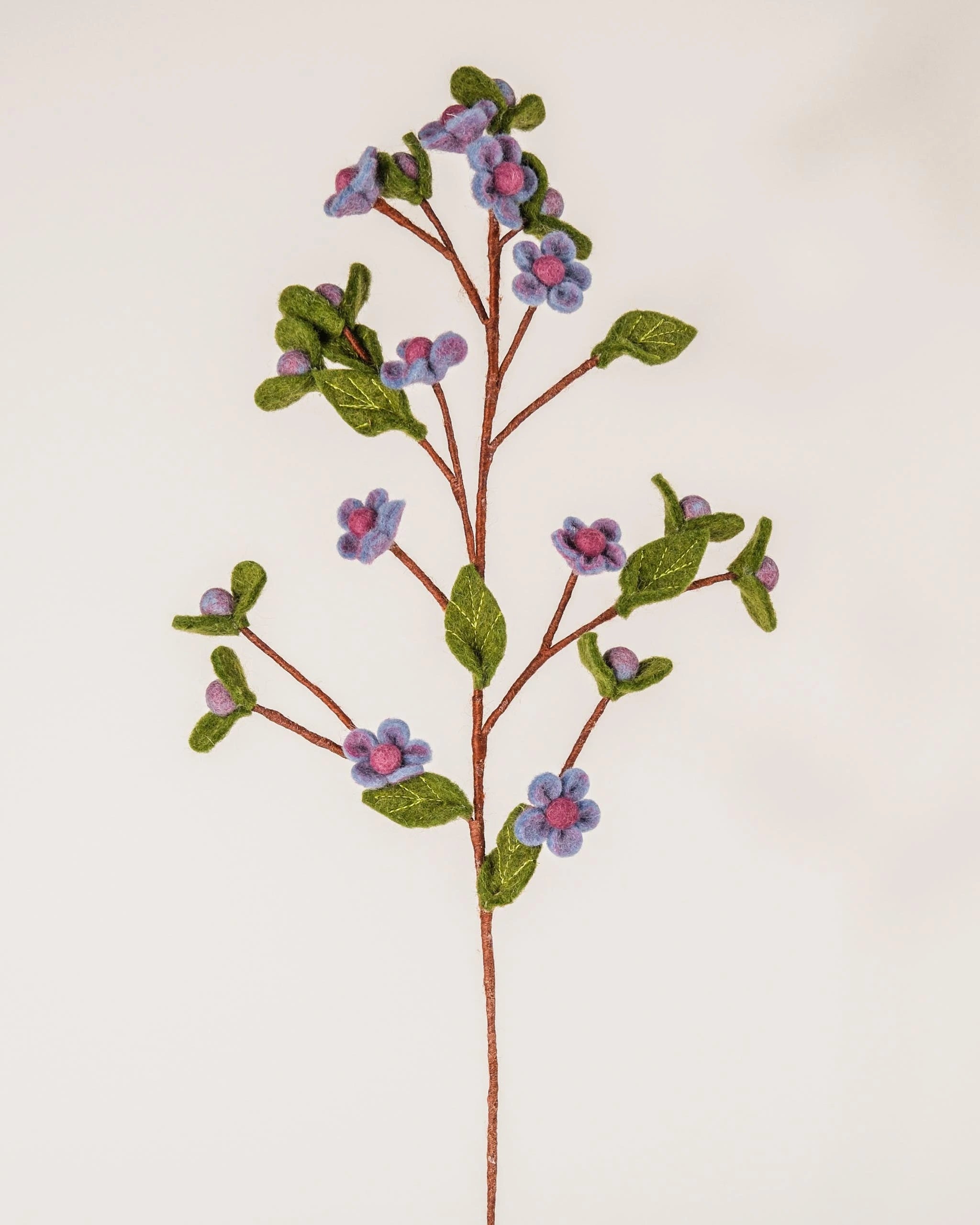 Photo d'une branche de fleur de prunier en feutrine sur un fond blanc.