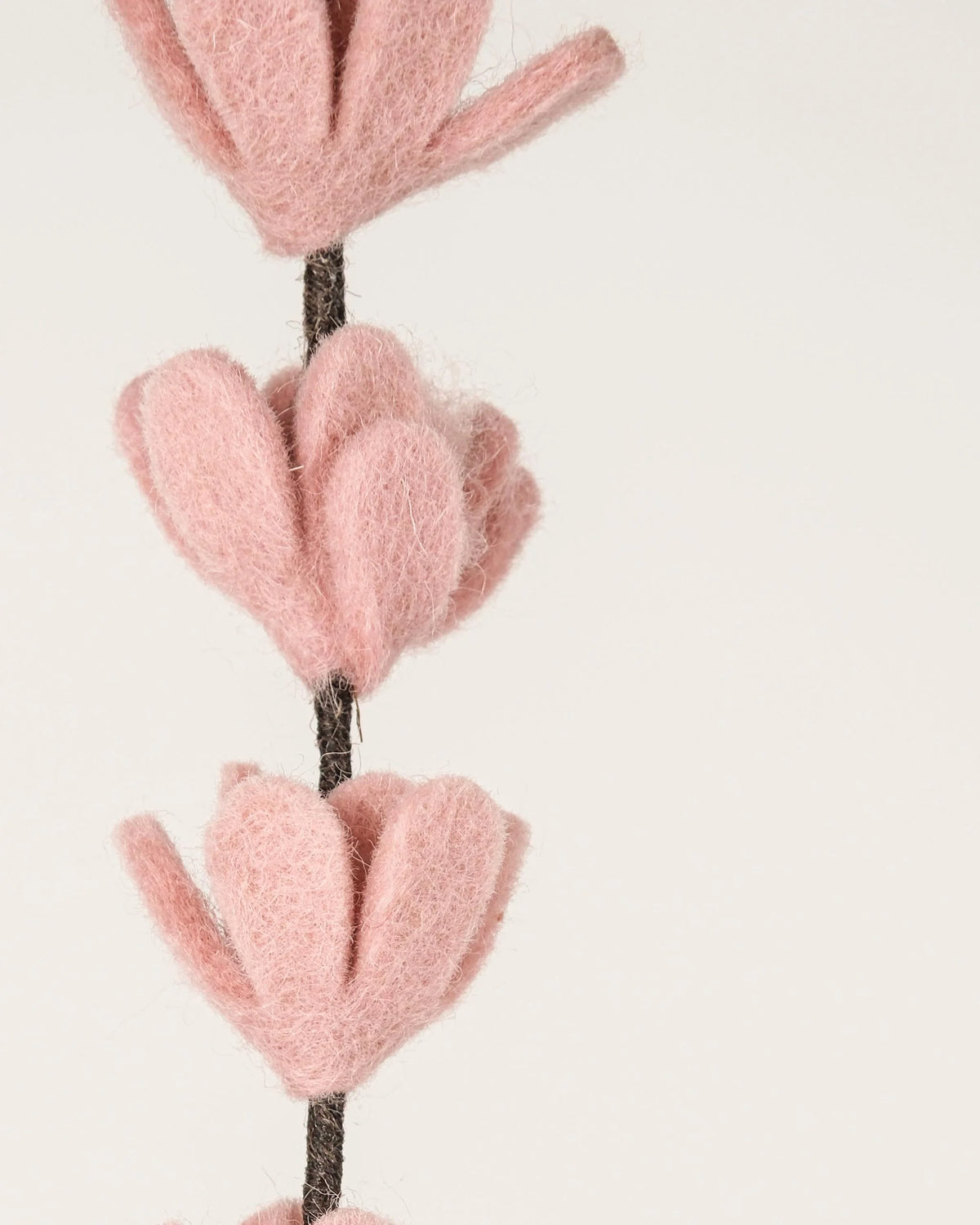 Photo zoom d'une branche de genêt rose pastel en feutrine sur un fond blanc style photo packshot.