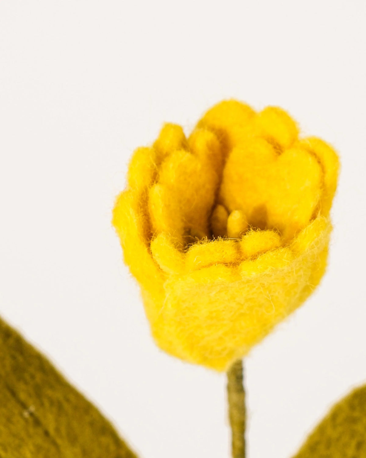 Photo zoom d'une tulipe jaune en feutrine sur un fond blanc style photo packshot.