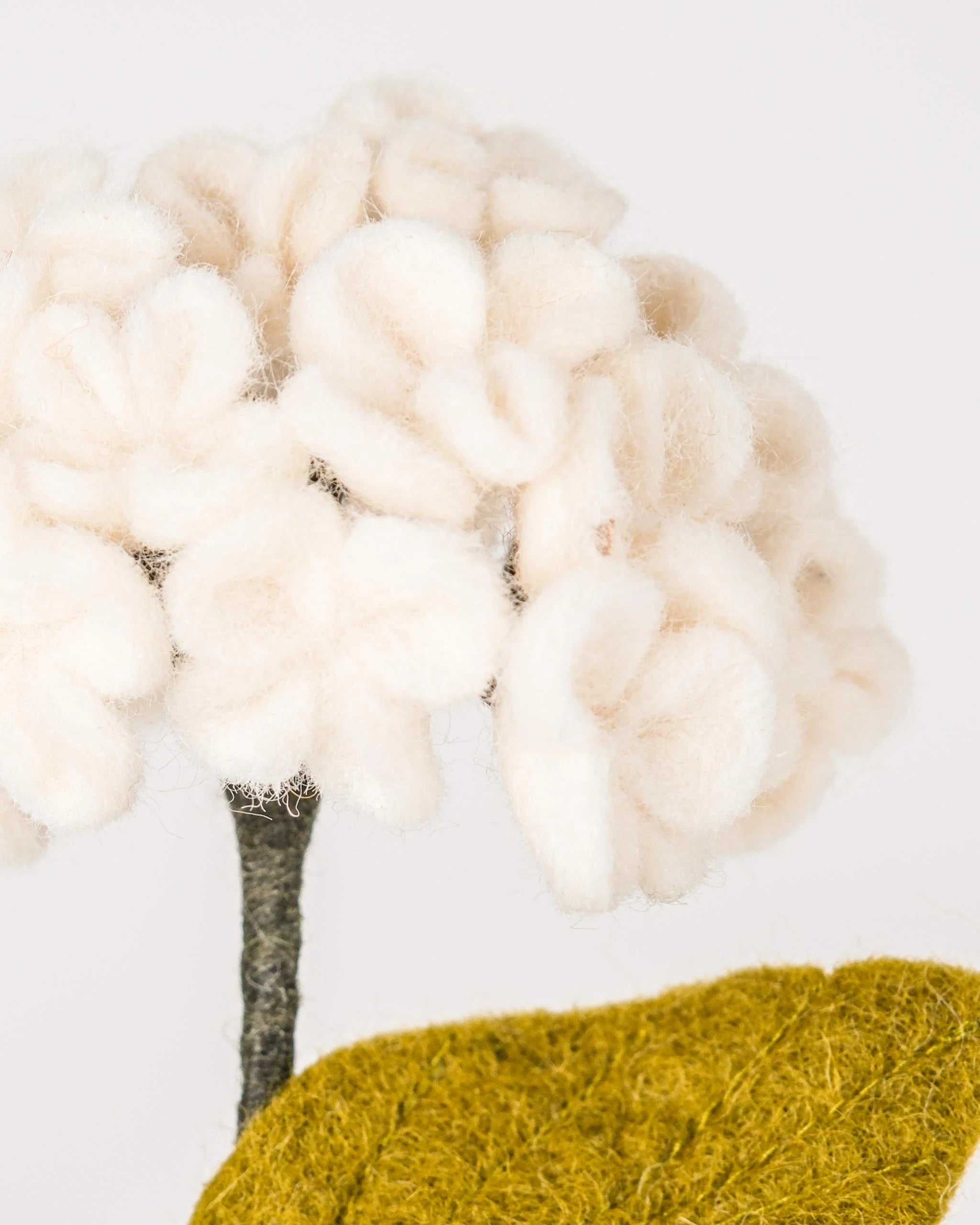 Photo zoom d'une hortensia blanche en feutrine sur un fond blanc.