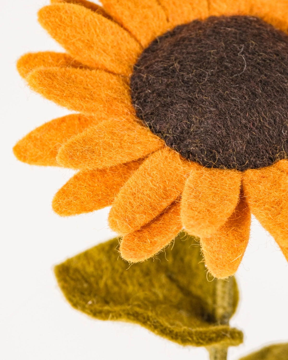 Photo zoom d'un tournesol en feutrine sur un fond blanc style photo packshot.