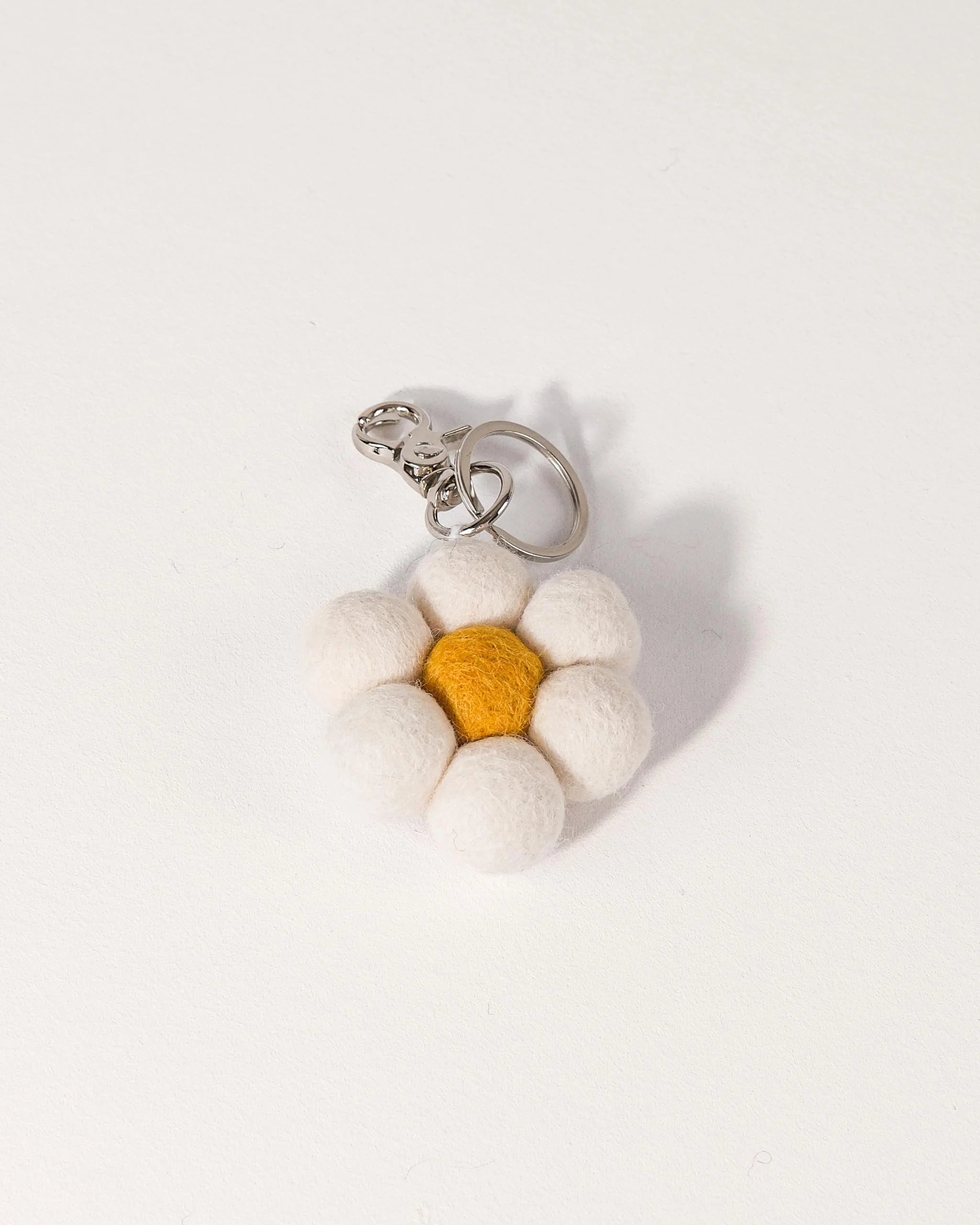 Porte clé marguerite en feutrine sur un fond blanc.