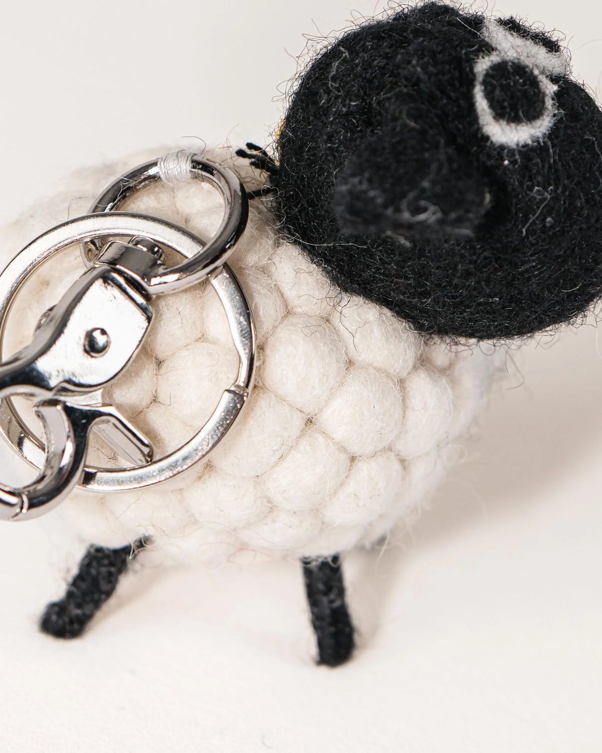 Porte clé mouton tête noir en feutrine sur un fond blanc détail zoom matère.
