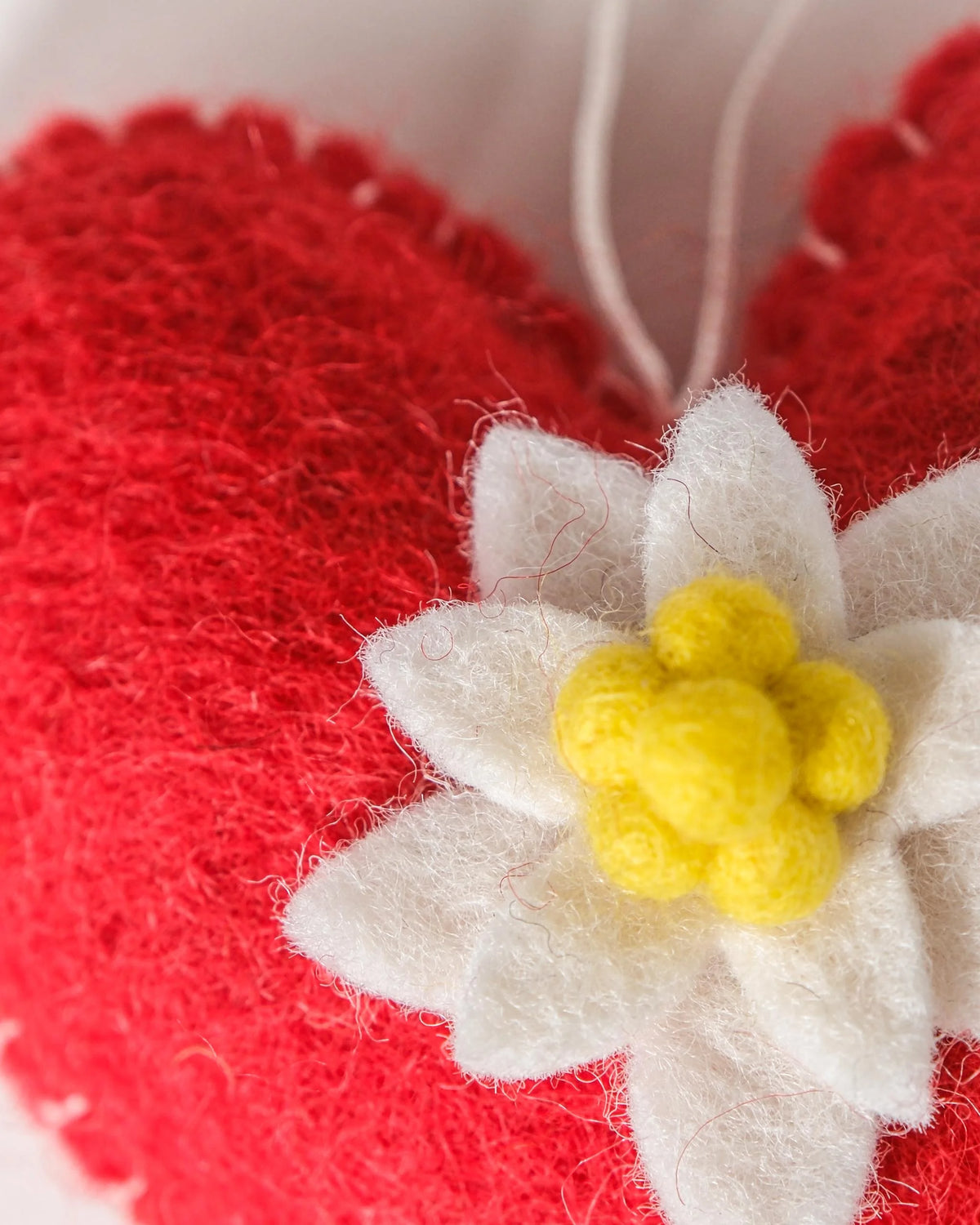 Coeur rouge a suspendre avec edelweiss sur fond blanc détail zoom matière.