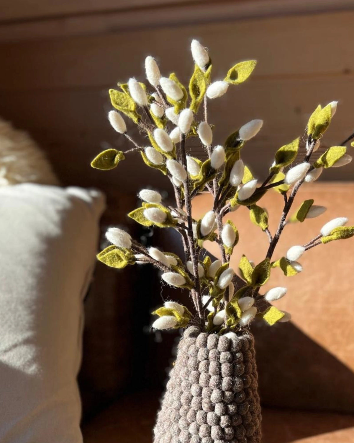 Vase en feutrine marron avec fleurs.