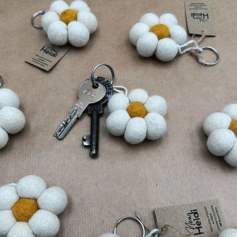 Porte-clé fleur en laine feutrée New Heidi utilisé avec un trousseau de clés sur fond kraft.