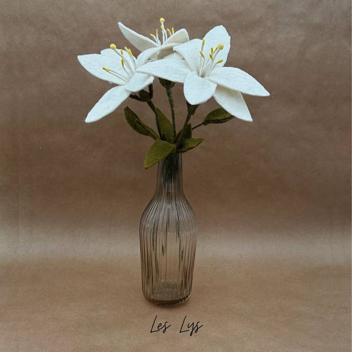 Bouquet de 3 lys éternels en laine New Heidi dans un vase en verre strié sur une table.