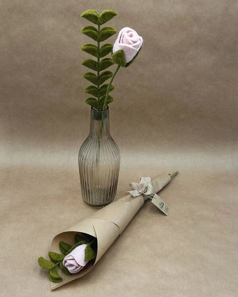 Bouquet de Saint-Valentin composé d'une rose rose et d'eucalyptus en feutrine New Heidi dans un vase et emballé dans du kraft.