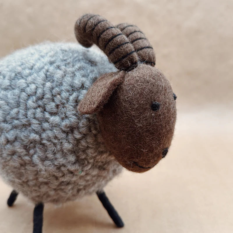 Gros plan sur la tête et les cornes striées artisanales du bouquetin géant New Heidi en laine feutrée.