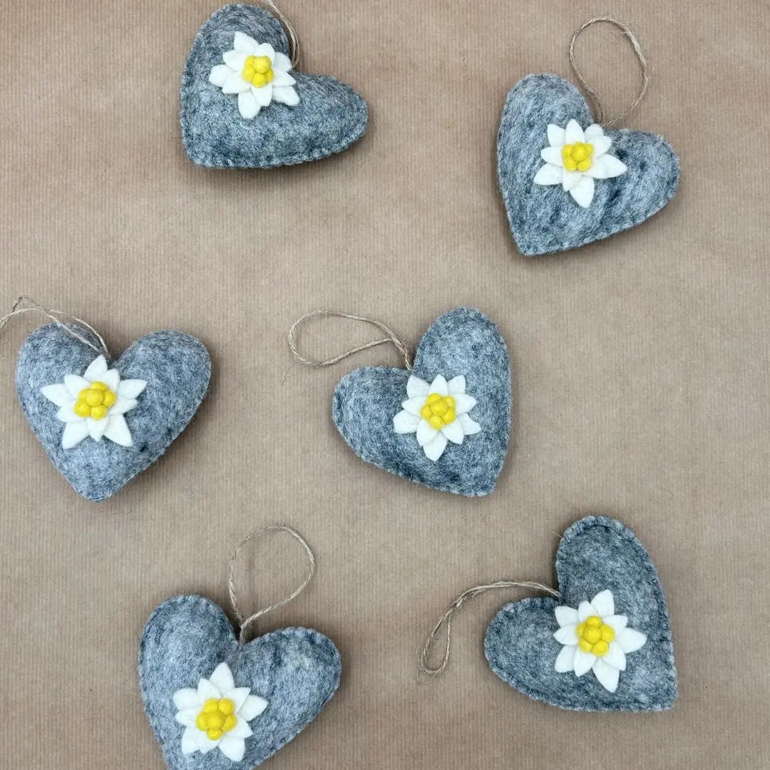 Groupe de cœurs décoratifs gris New Heidi avec fleur d'edelweiss blanche à suspendre sur fond kraft.