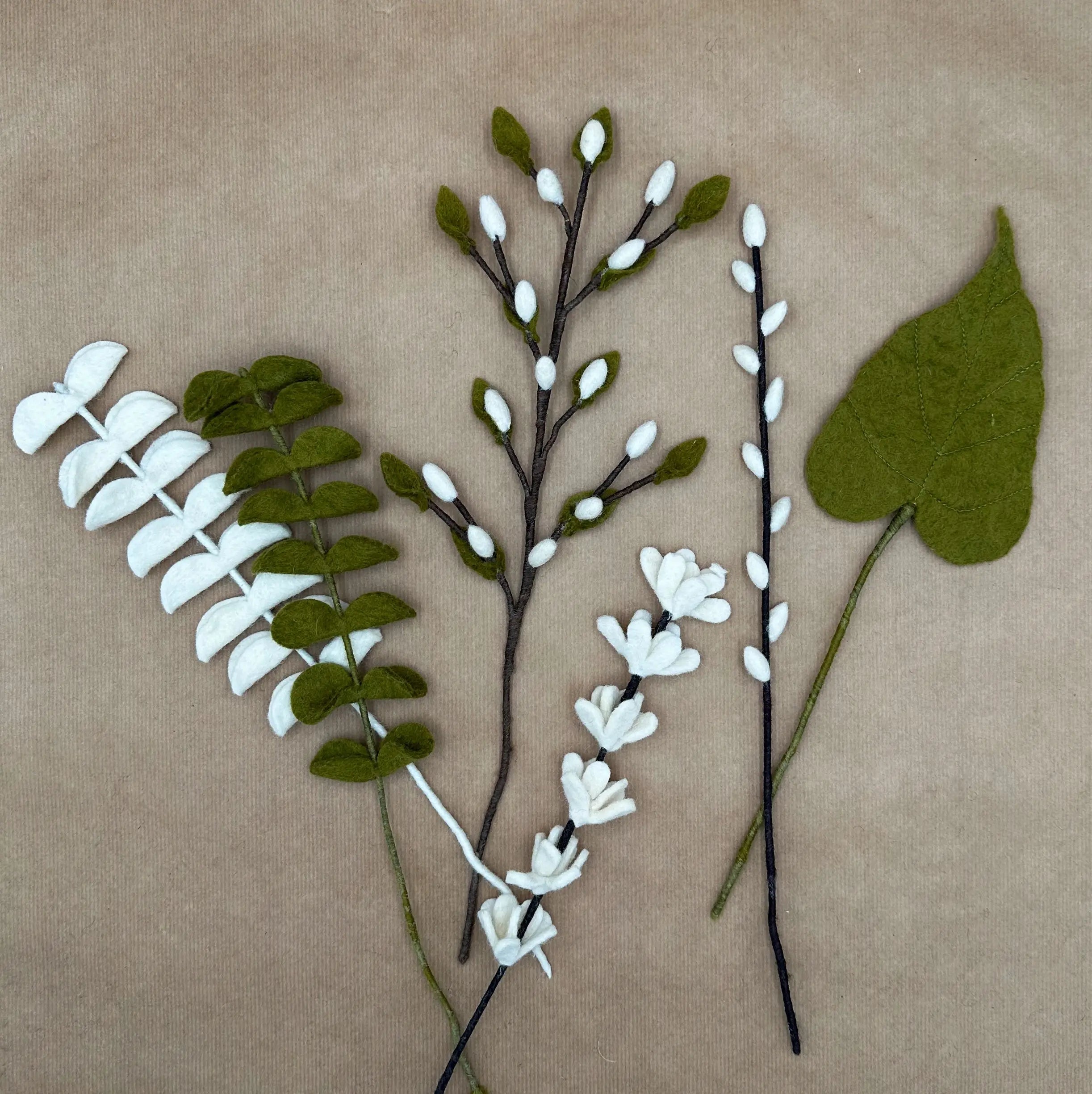 Présentation des différentes tiges artisanales (eucalyptus, saule, arum, genêt) du bouquet Brume de Forêt.