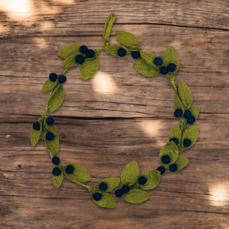 Couronne décorative de myrtilles New Heidi en laine feutrée posée sur un fond en bois rustique.