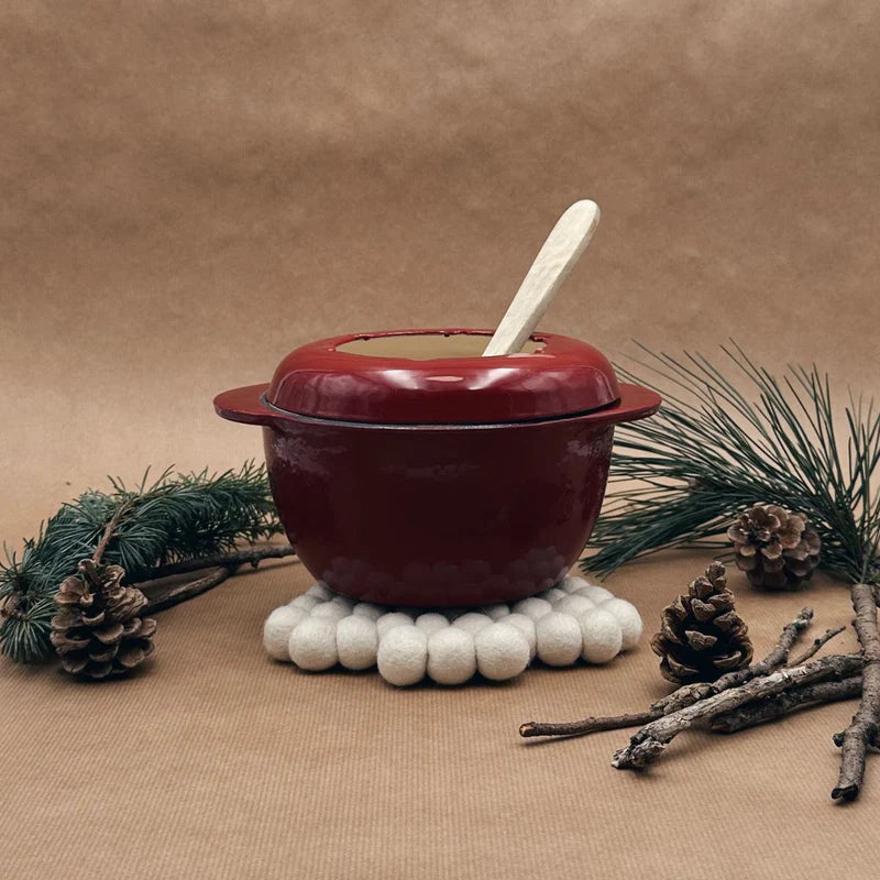 Dessous de plat New Heidi en forme de sapin composé de boules de feutrine blanches posé sous une marmite.