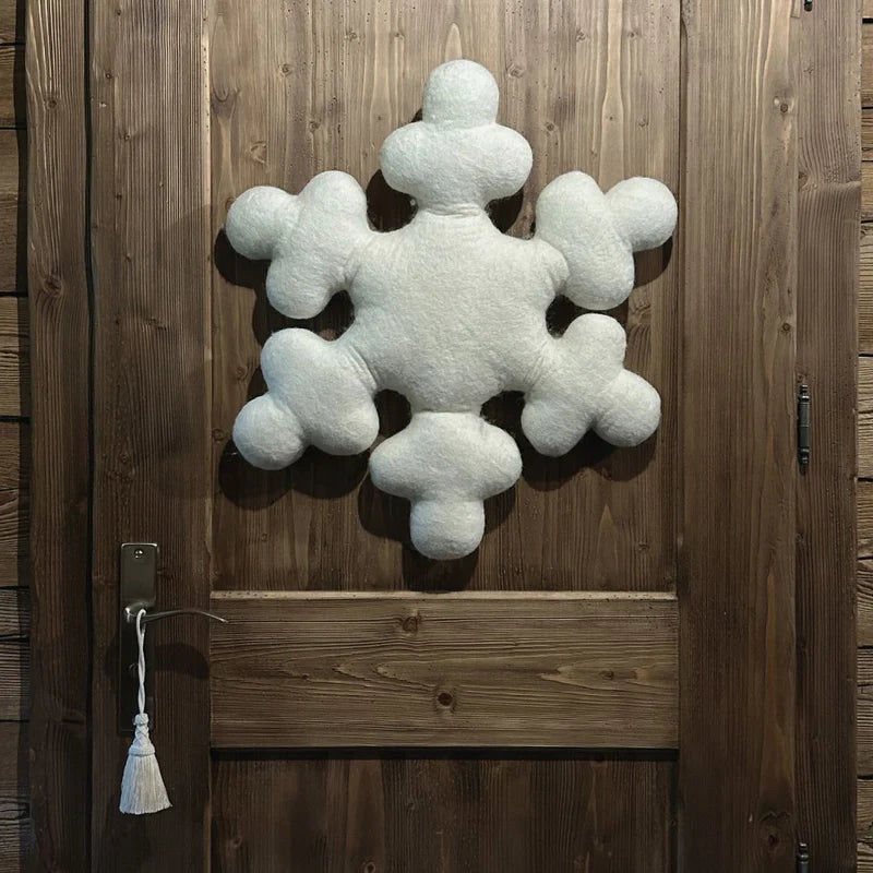 Coussin flocon New Heidi suspendu sur une porte en bois massif comme décoration de Noël artisanale.