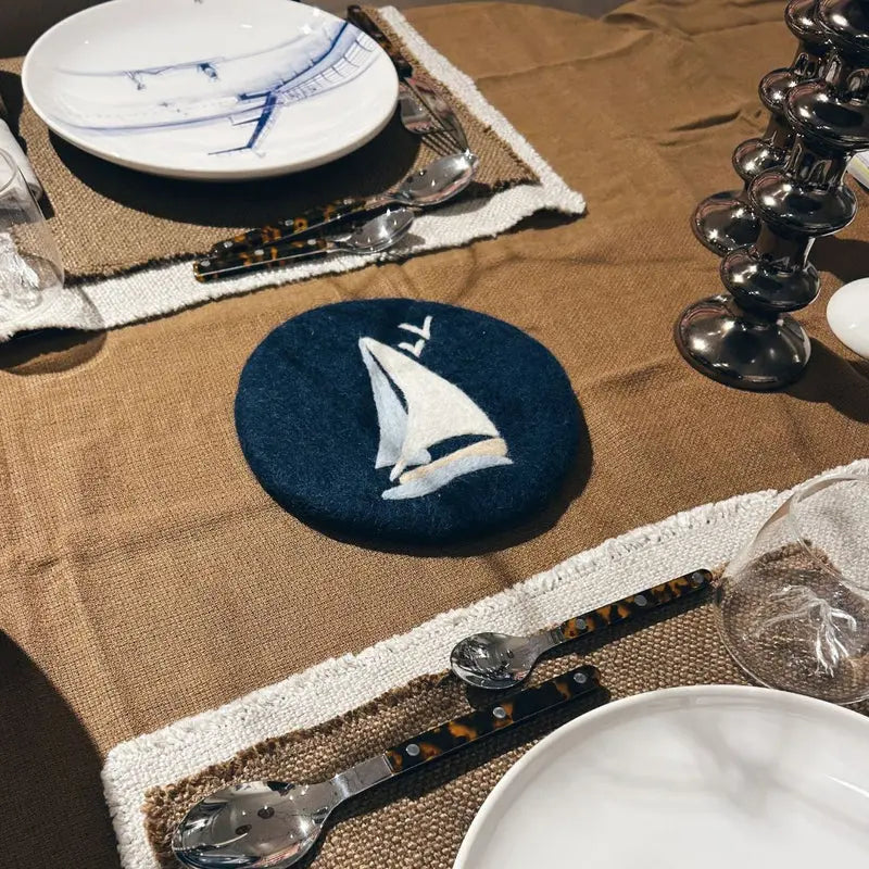 Ambiance de table maritime avec le dessous de plat ancre supportant une théière chaude.