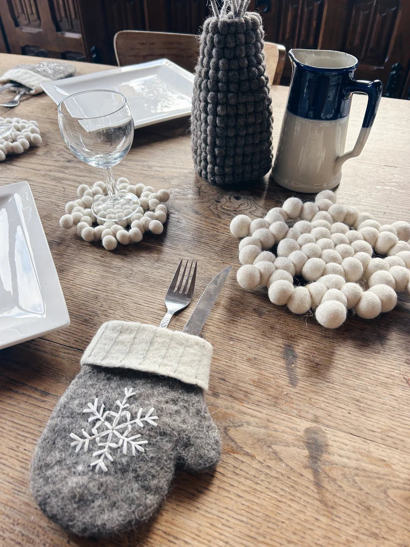 Présentation d'une table de fête avec le gant à couverts flocon New Heidi et des accessoires en laine.