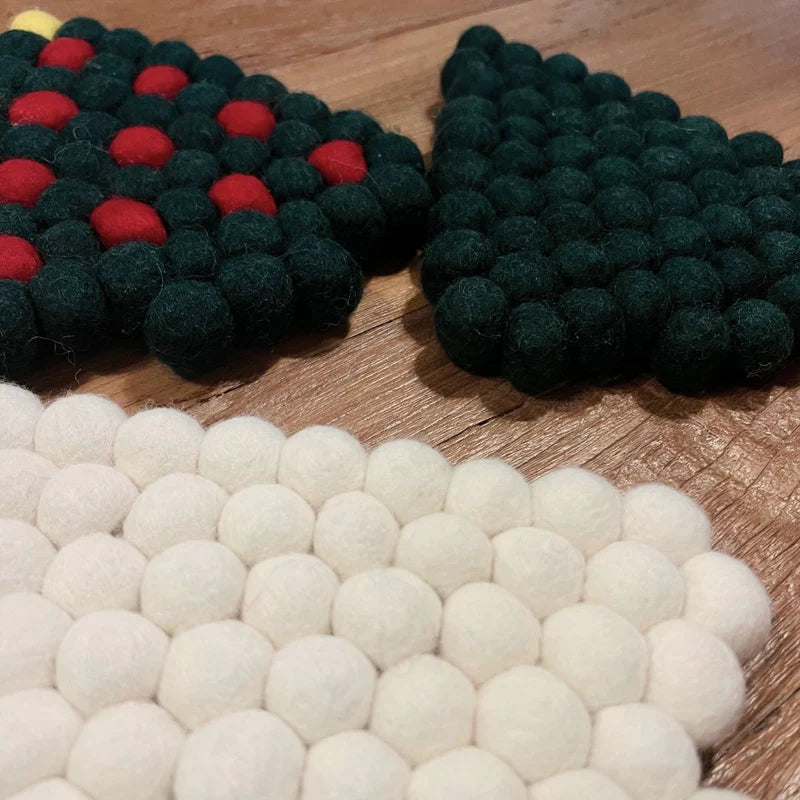 Décoration de table hivernale avec le dessous de plat sapin en boules de feutrine et éléments naturels.