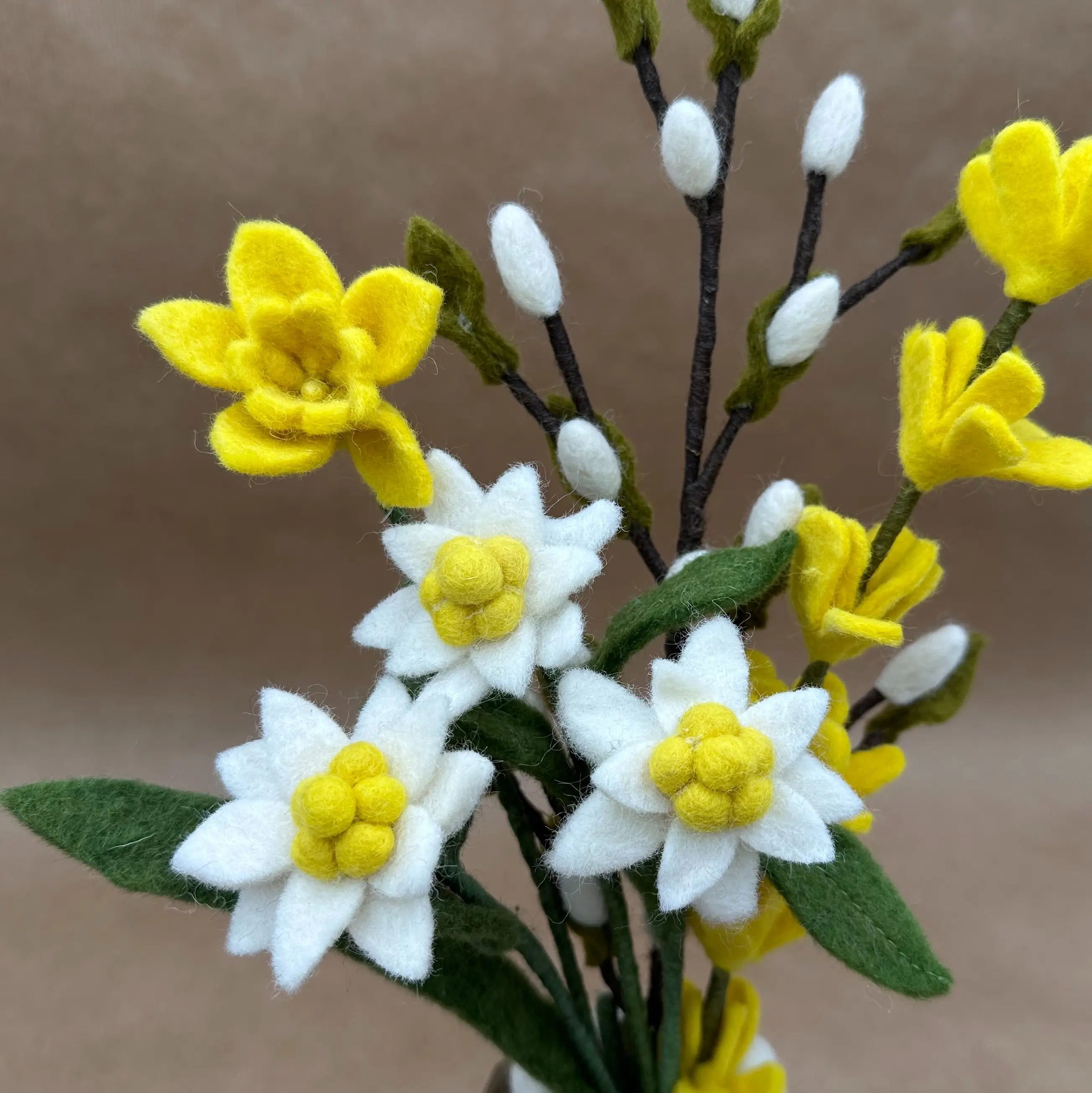 Zoom sur les détails artisanaux des edelweiss blanches et des jonquilles jaunes en feutrine New Heidi.