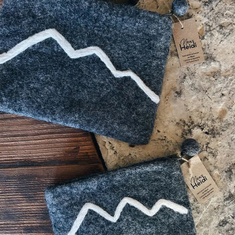 Gros plan de la pochette sur la texture de la laine et l'étiquette New Heidi, fabrication artisanale au Népal.