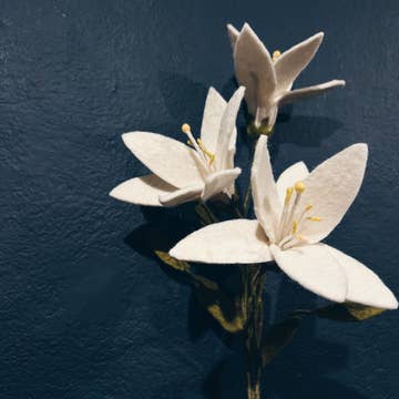 Gros plan sur les pétales et pistils d'un lys en feutrine fait main New Heidi sur fond sombre.