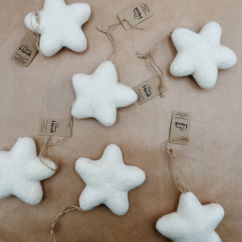 Groupe d'étoiles de Noël à suspendre New Heidi en laine feutrée blanche avec étiquettes sur fond kraft.