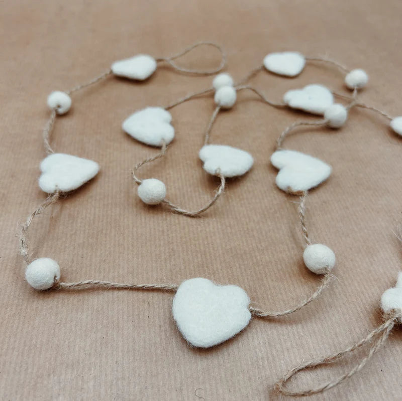 Détail de la guirlande cœur New Heidi en laine posée sur fond kraft, fabrication solidaire du Népal.