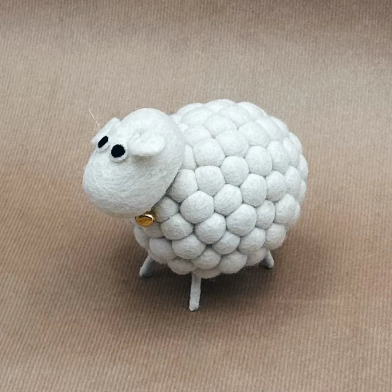 Gros plan sur la figurine mouton New Heidi en laine feutrée avec sa petite clochette.