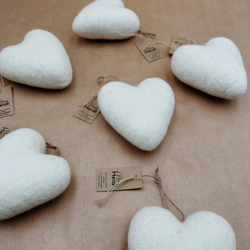 Composition de plusieurs cœurs en feutrine blanche suspendus pour une décoration murale poétique.