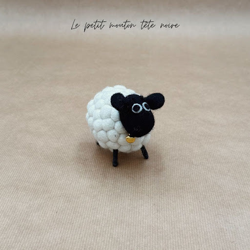 Petit mouton tête noire New Heidi en feutrine blanche bouclée artisanale vue de profil avec petite cloche.