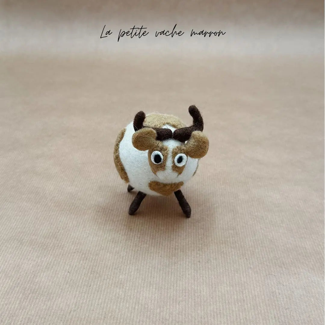 Petite vache boule marron et blanche New Heidi en feutrine artisanale vue de face.