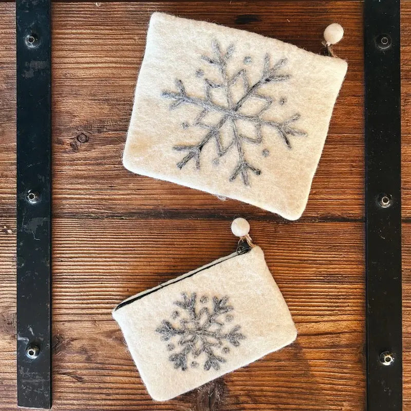Deux pochettes blanches motif flocon sur un plateau en bois rustique, accessoires New Heidi.