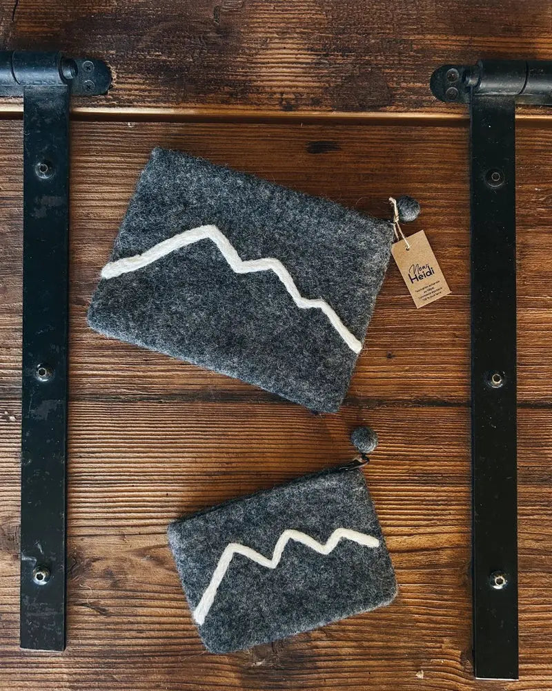 Duo de pochettes New Heidi en feutrine grise avec broderie montagne blanche sur support bois.