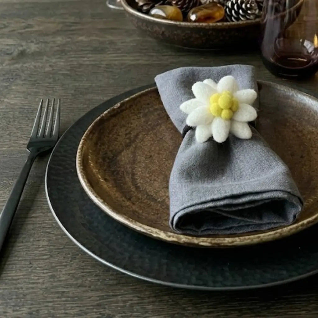 Rond de serviette artisanal edelweiss New Heidi sur une serviette grise.