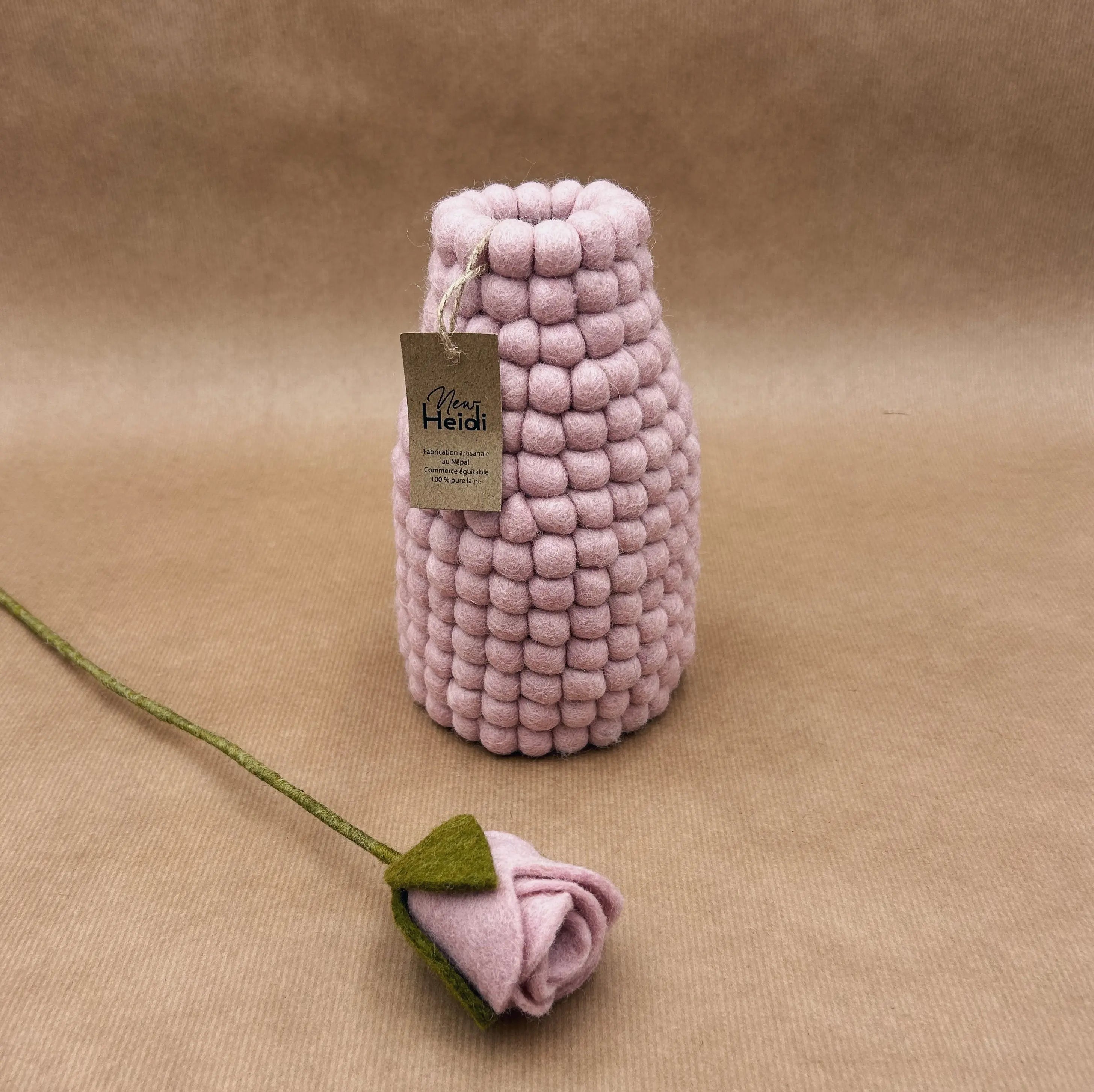 Vase en laine feutrée rose New Heidi avec son étiquette artisanale, accompagné d'une rose rose en feutrine.