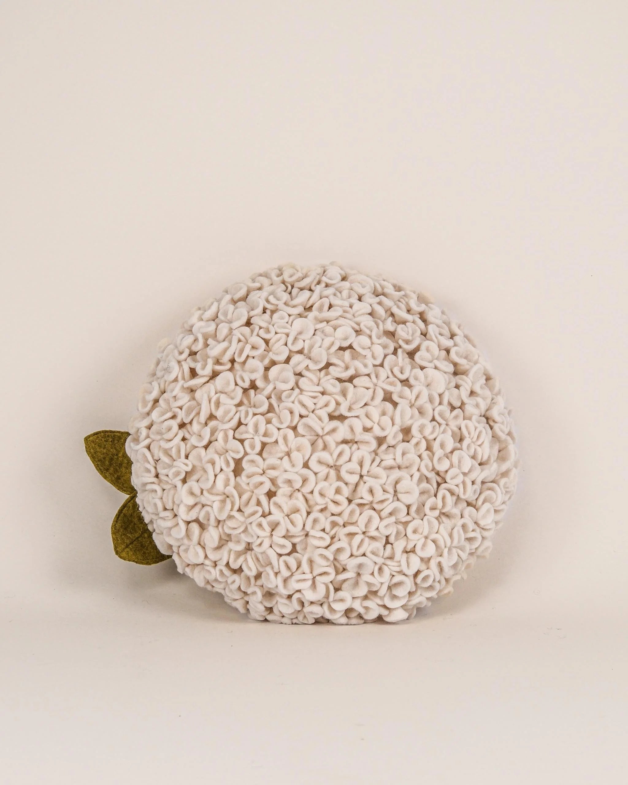 Coussin décoratif hortensia en feutrine sur fond blanc.